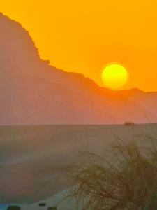 a sunset on the beach with the sun setting at Ammar Rum Camp and jeep tour in Wadi Rum