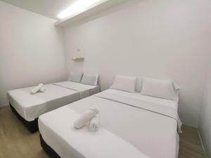 two beds in a room with white walls at Maco Inn Century @Johor Bahru in Johor Bahru