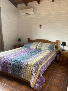 1 dormitorio con 1 cama con un edredón colorido en Casa 7 Cerros en Piriápolis