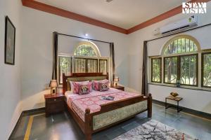 a bedroom with a bed and two windows at Jungle Retreat by VEO - Part of StayVista in Bāli