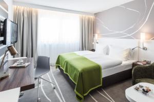 a hotel room with a bed with a green blanket at Holiday Inn Munich City Centre, an IHG Hotel in Munich