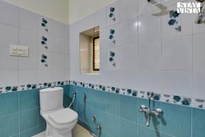 a bathroom with a toilet and blue and white tiles at Jungle Retreat by VEO - Part of StayVista in Bāli +19 photos
