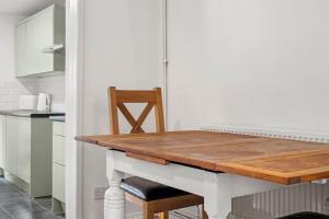 uma cozinha com uma mesa de madeira e 2 cadeiras em Hoan Place em Strood
