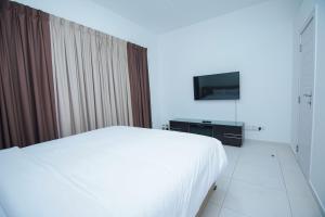 a bedroom with a white bed and a television at Home Away Holiday Homes in Dubai