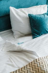 a bed with white sheets and a blue pillow at Hotel Nais in Niš