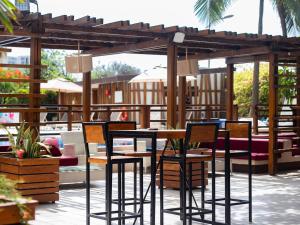 eine Terrasse mit Stühlen, einem Tisch und einer Pergola in der Unterkunft Novotel Dakar in Dakar