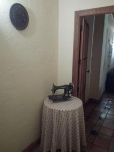 een tafel met een tafelkleed en een klok aan een muur bij La Casa de la Abuela in Cazorla