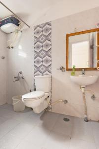 La salle de bains est pourvue de toilettes, d'un lavabo et d'un miroir. dans l'établissement Stayhome Suites, à Bangalore