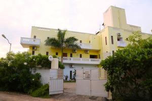 una casa amarilla con una cerca blanca delante de ella en Shangrila at blissful haven near to Matrimandir en Auroville