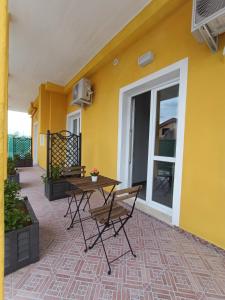 a patio with a table and chairs next to a yellow wall at Costa di Sopra Affittacamere in Quartu SantʼElena