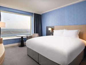 a large bed in a hotel room with a large window at Sofitel London Gatwick in Horley