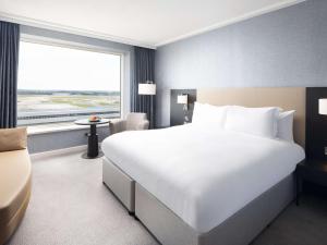 a large white bed in a hotel room with a window at Sofitel London Gatwick in Horley