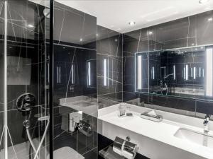a bathroom with a shower and a sink and a mirror at Sofitel London Gatwick in Horley