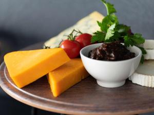a plate with cheese and a bowl of sauce and tomatoes at Sofitel London Gatwick in Horley