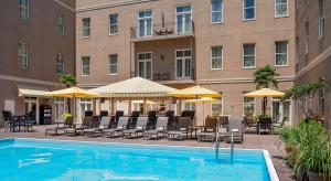 a hotel with a swimming pool and chairs and umbrellas at Hyatt Centric French Quarter in New Orleans