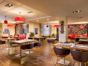 a restaurant with wooden tables and chairs and red chairs at ibis Kyiv City Center in Kyiv