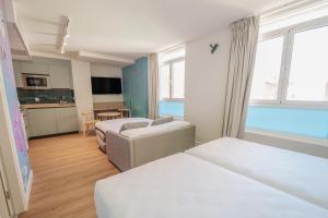 a hotel room with two beds and a kitchen at Apartamentos Valladolid Centro in Valladolid