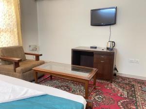 a hotel room with a bed and a table and a tv at Aadi's Residency in Gurgaon