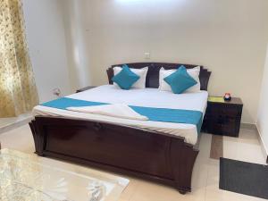 a large bed with blue pillows in a bedroom at Aadi's Residency in Gurgaon