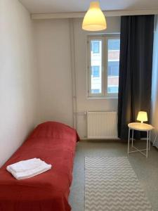 Cama roja en habitación con ventana en Kotimaailma - Kalustettu saunallinen asunto kuudelle en Vantaa