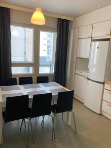 a kitchen with a table and chairs and a refrigerator at Kotimaailma - Kalustettu saunallinen asunto kuudelle in Vantaa