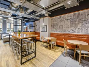 um restaurante com mesas e cadeiras e uma parede com mapas em ibis Styles Glasgow Centre George Square em Glasgow