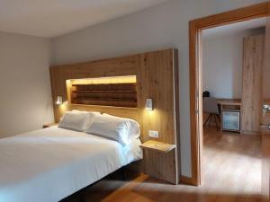 a bedroom with a large bed with a wooden headboard at Hotel Saurat in Espot