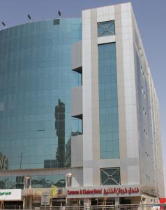 a tall glass building with a clock on it at Carawan Al Khaleej Hotel Olaya in Riyadh