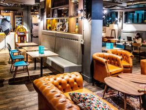 un restaurante con sofás de cuero, mesas y sillas en ibis Styles Glasgow Central en Glasgow