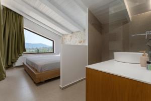 ein Bad mit einem Waschbecken, einem Bett und einem Fenster in der Unterkunft Evylio Stone Houses in Lithakia