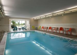 a large swimming pool with orange chairs and a table at Home2 Suites Troy, OH in Troy