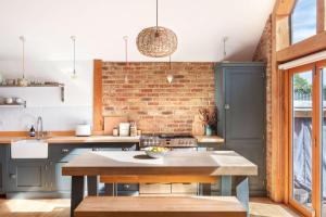 a kitchen with blue cabinets and a brick wall at Badgers Cottage in Fittleworth