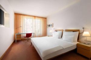 a hotel room with a large white bed and a desk at Vienna House by Wyndham Andel's Prague in Prague