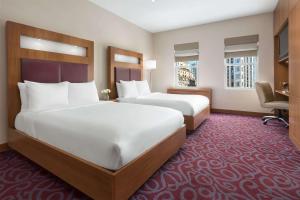 Cette chambre comprend deux lits et un bureau. dans l'établissement Hotel 57 by LuxUrban, à New York