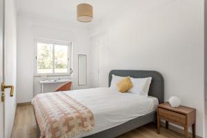 a white bedroom with a bed and a window at JOIVY Striking flat in Benfica in Lisbon