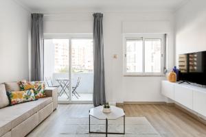 a white living room with a couch and a tv at JOIVY Striking flat in Benfica in Lisbon