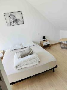 Una cama con sábanas blancas y almohadas. en Appart T3 neuf à 15 min d’Angers, en Corné
