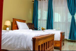 a bedroom with a large bed with blue curtains at CAR-NET HOTEL in Kisoro