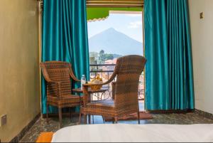 een kamer met 2 stoelen, een tafel en een raam bij CAR-NET HOTEL in Kisoro