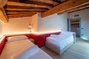 two beds in a room with wooden ceilings at Palazzo Reggiani - Leonardo Da Vinci in Verona +29 photos