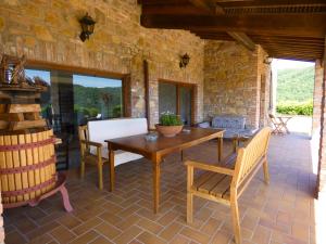 um pátio com uma mesa e cadeiras de madeira e uma parede de pedra em Scappo in Umbria, la Vallata em Parrano