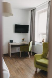 a living room with a desk and a tv and a chair at Hotel am Stadtpark Nordhausen in Nordhausen