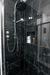 a bathroom with a shower with black tiles at Modern apartment in Aberdeen City Centre, Guild street, free WiFi in Aberdeen