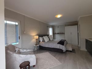 a bedroom with a bed and a chair and a couch at Private & Spacious Olive cottage in Bloubergstrand in Cape Town