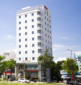 um edifício branco com carros estacionados em frente em Phú An Hotel em Da Nang