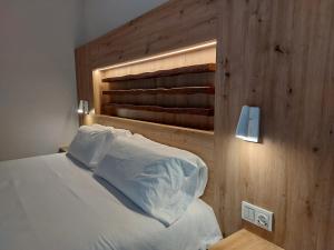 a bedroom with a white bed with a wooden headboard at Hotel Saurat in Espot