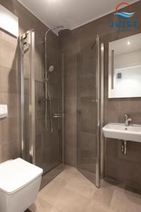 ein Bad mit einer Dusche, einem WC und einem Waschbecken in der Unterkunft Haus Billstrasse 231 - Wohnung 1 in Juist