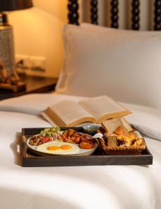 ルアンパバーンにあるV Maison Boutique Hotelのベッドの上に朝食用の食品のトレイ