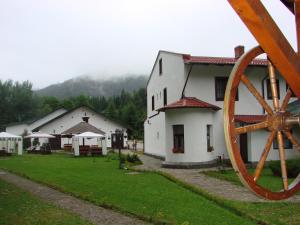 a group of white buildings with a large wooden wheel at Pensiunea Rhein in Azuga