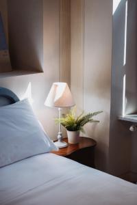 um quarto com uma cama e um candeeiro sobre uma mesa em Hotel Oviv dimora del borgo em Acquaviva Picena
